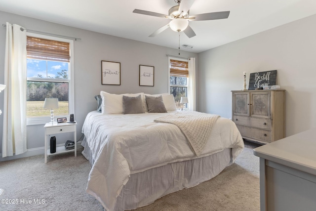 bedroom featuring light carpet, multiple windows, visible vents, and a ceiling fan