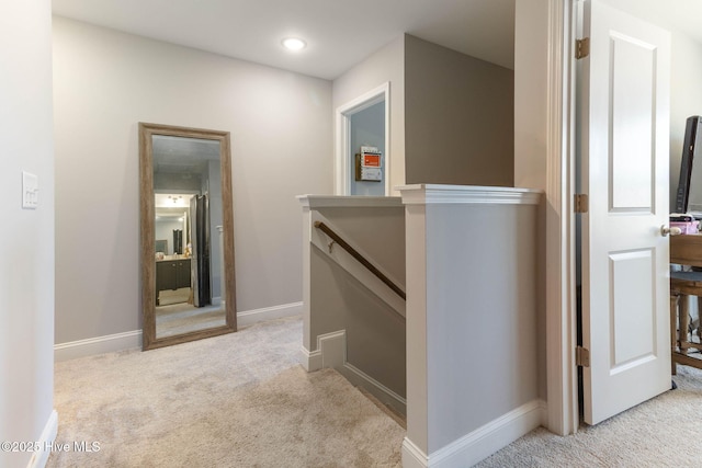 hallway with carpet, baseboards, and an upstairs landing