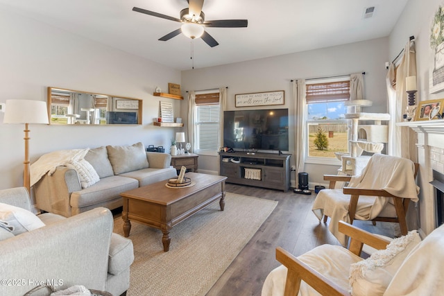 living area featuring a fireplace, visible vents, ceiling fan, wood finished floors, and baseboards