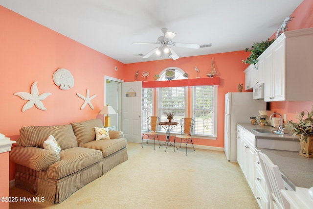 living room featuring visible vents, baseboards, a ceiling fan, and light colored carpet