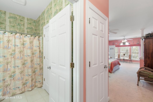 corridor featuring light carpet, ornate columns, and wallpapered walls