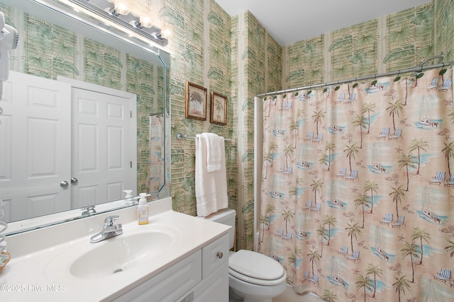 bathroom with curtained shower, vanity, toilet, and wallpapered walls