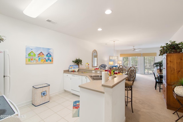 kitchen with a peninsula, white appliances, a breakfast bar, visible vents, and white cabinetry