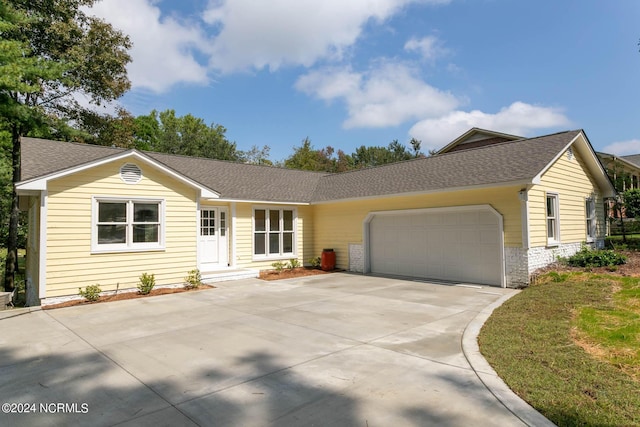 ranch-style house featuring a garage, driveway, and roof with shingles