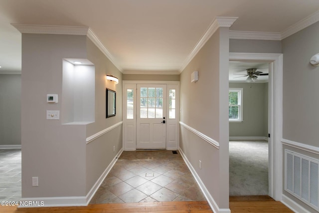 foyer with baseboards, visible vents, ceiling fan, tile patterned floors, and crown molding