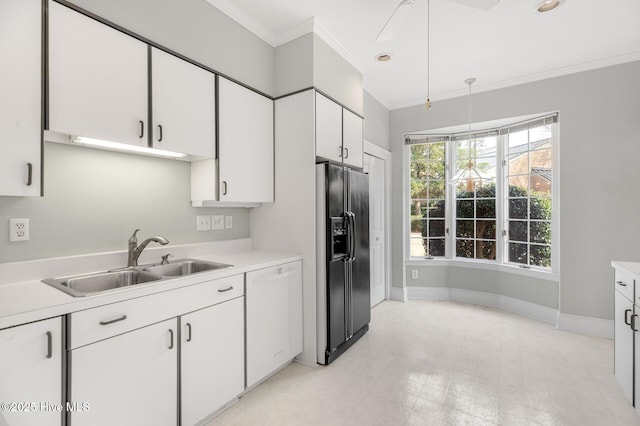 kitchen with light countertops, ornamental molding, white cabinets, a sink, and black fridge