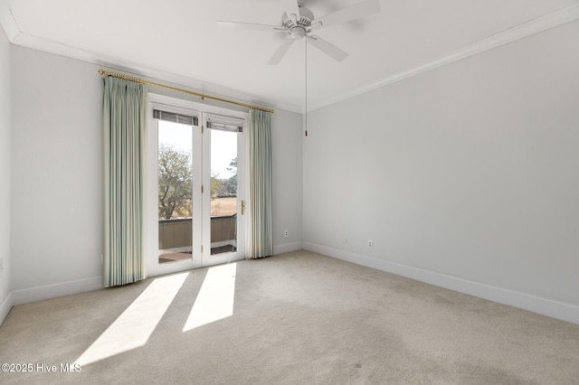 carpeted empty room with a ceiling fan, baseboards, and crown molding