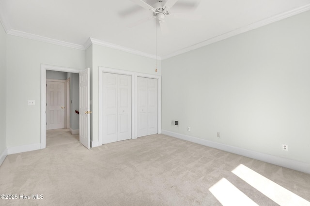 unfurnished bedroom with multiple closets, visible vents, ornamental molding, light carpet, and baseboards