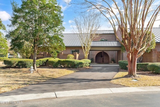 view of front of home with driveway, metal roof, a standing seam roof, a carport, and brick siding