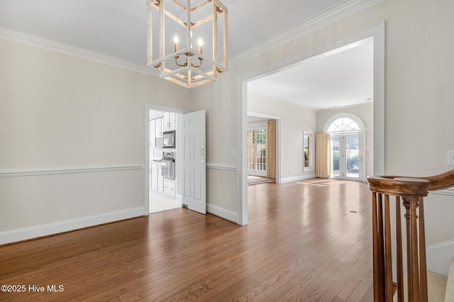 entrance foyer with ornamental molding, an inviting chandelier, baseboards, and wood finished floors