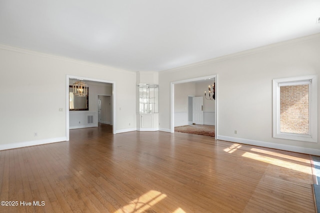 unfurnished living room featuring ornamental molding, baseboards, and wood finished floors