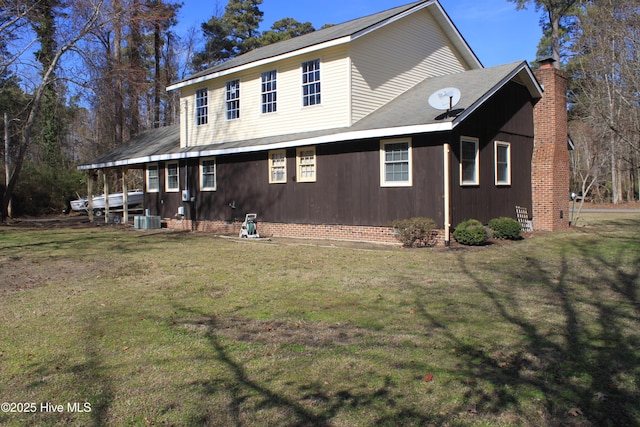 exterior space featuring a lawn, a chimney, and cooling unit