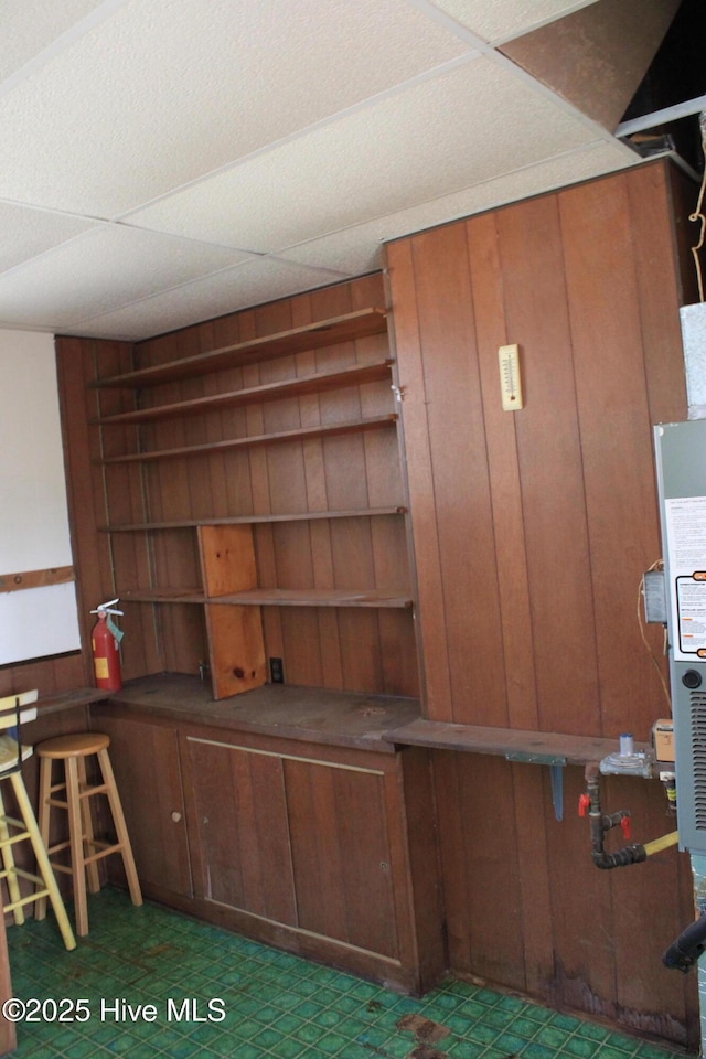 unfurnished office featuring wood walls, a paneled ceiling, and tile patterned floors