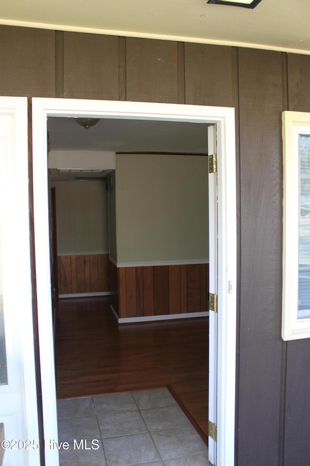 hallway with light tile patterned floors and wooden walls