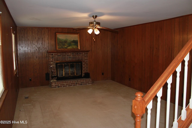 unfurnished living room with a brick fireplace, carpet flooring, and wooden walls