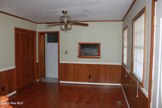 unfurnished room with wood finished floors, a ceiling fan, and crown molding