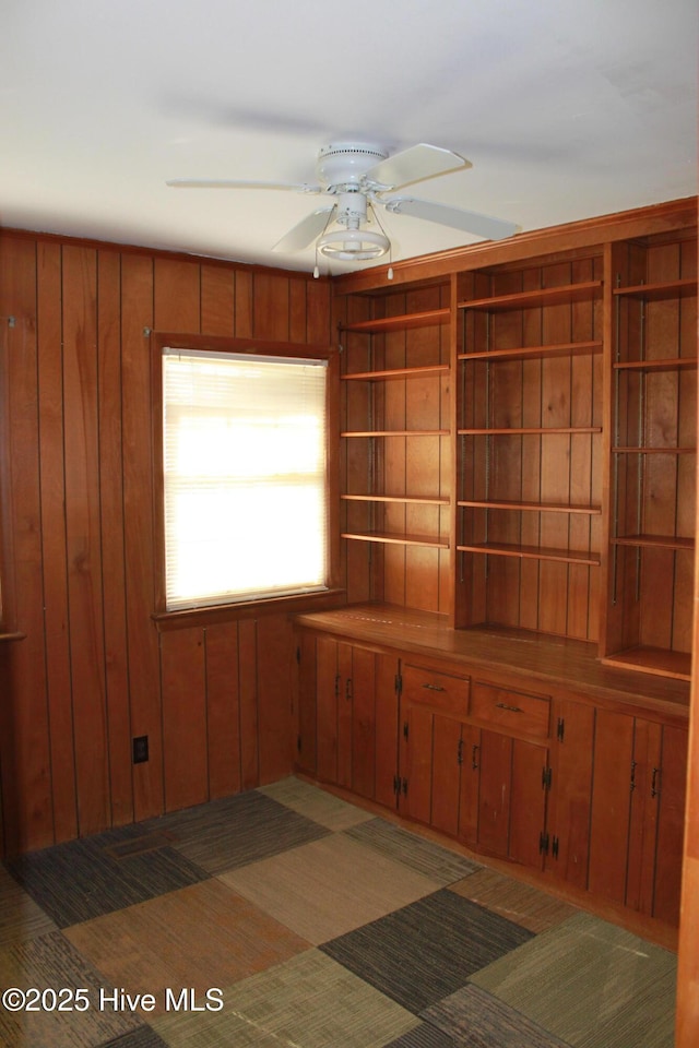 spare room with wood walls and a ceiling fan