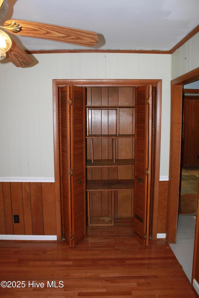 corridor with ornamental molding and wood finished floors