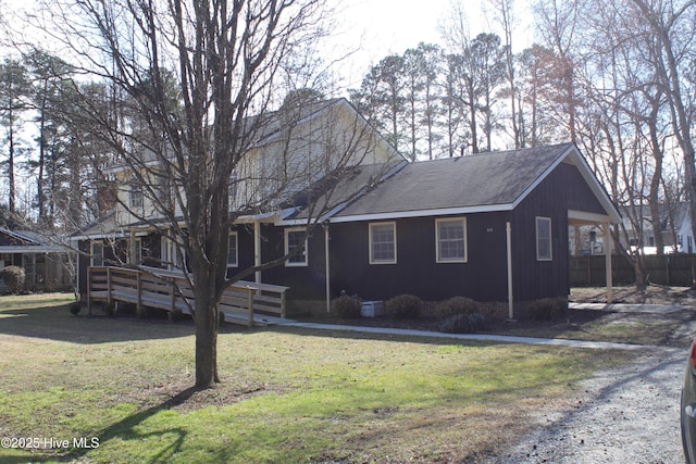 ranch-style home with roof with shingles, a deck, and a front yard