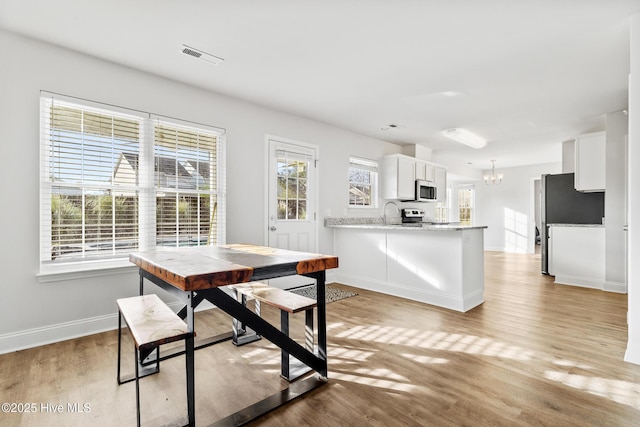 dining room featuring an inviting chandelier, light wood-style floors, baseboards, and visible vents