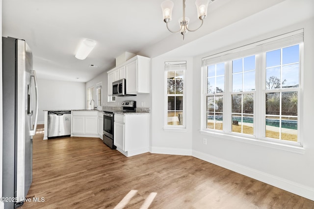 kitchen featuring a notable chandelier, wood finished floors, baseboards, and appliances with stainless steel finishes