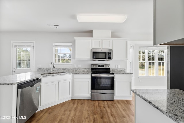 kitchen featuring a sink, light stone countertops, appliances with stainless steel finishes, and white cabinets