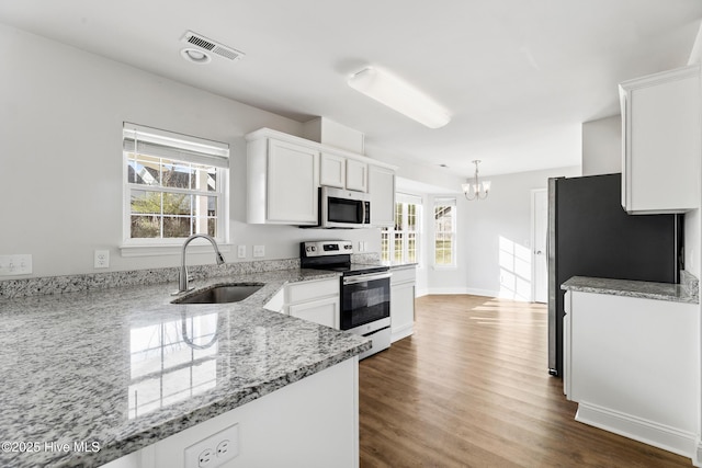 kitchen featuring visible vents, a notable chandelier, a sink, white cabinetry, and stainless steel appliances