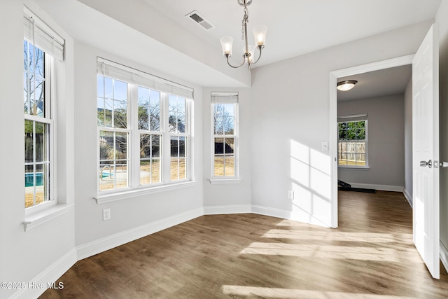 unfurnished dining area with a wealth of natural light, visible vents, baseboards, and wood finished floors