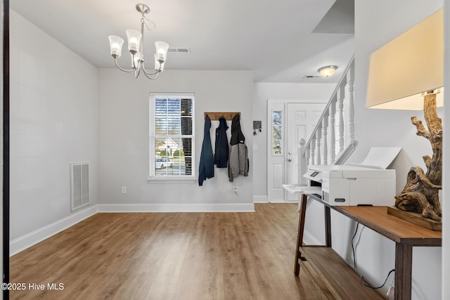 entryway featuring visible vents, baseboards, a notable chandelier, and wood finished floors