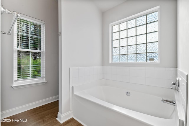 full bathroom featuring baseboards, wood finished floors, and a bath