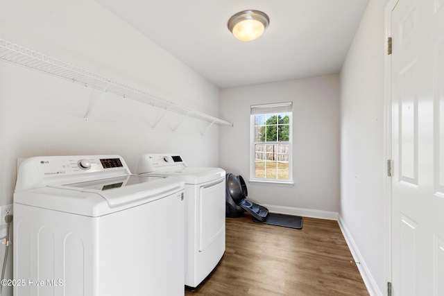 washroom featuring dark wood finished floors, laundry area, separate washer and dryer, and baseboards