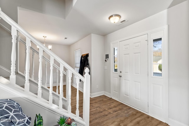 foyer entrance featuring stairway, wood finished floors, visible vents, and baseboards