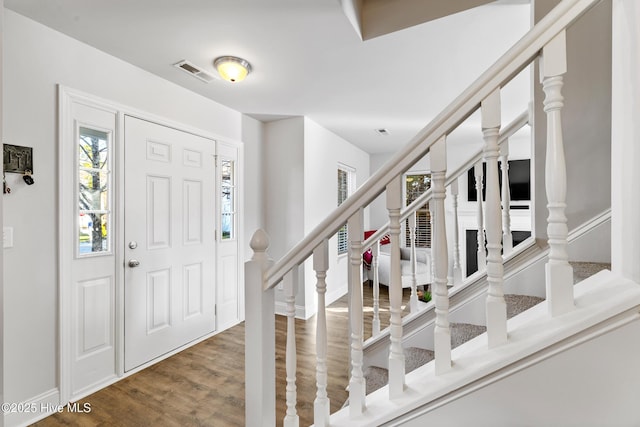 entrance foyer with visible vents, stairway, and wood finished floors