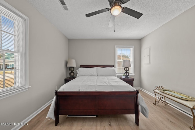 bedroom featuring visible vents, a ceiling fan, a textured ceiling, wood finished floors, and baseboards