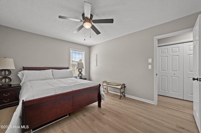 bedroom with light wood-type flooring, ceiling fan, baseboards, and a textured ceiling