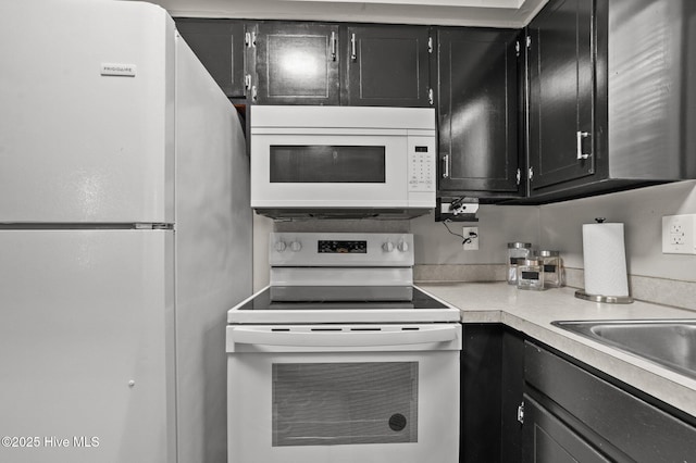 kitchen featuring light countertops, white appliances, and dark cabinetry