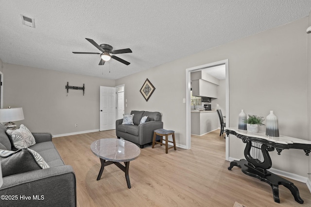 living area with light wood-style floors, baseboards, visible vents, and a ceiling fan