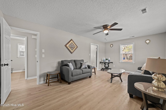 living area featuring a ceiling fan, visible vents, light wood-style flooring, and baseboards