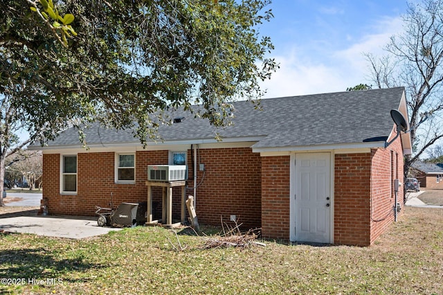 rear view of house featuring a patio area, a shingled roof, a lawn, and brick siding