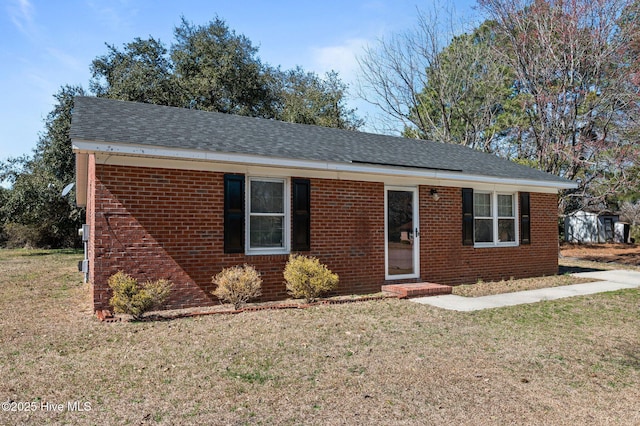 single story home with roof with shingles, a front lawn, and brick siding