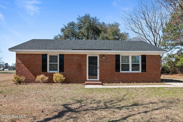 ranch-style house featuring roof with shingles, a front lawn, and brick siding