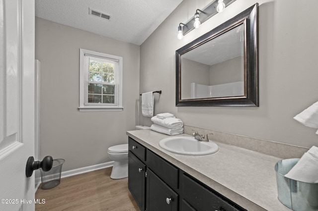 bathroom featuring baseboards, visible vents, wood finished floors, a textured ceiling, and vanity