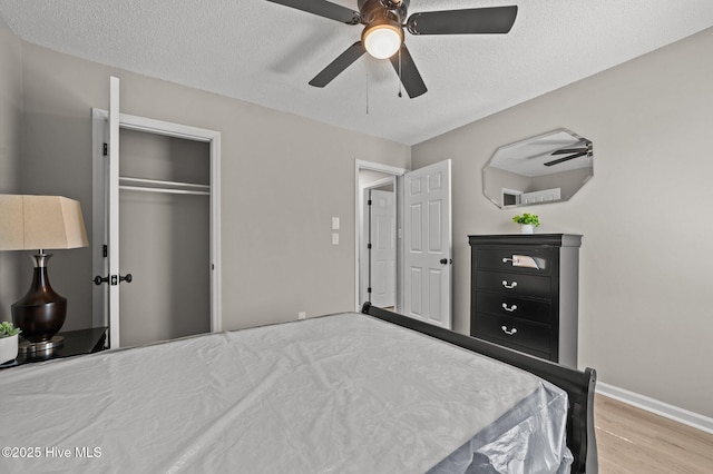 bedroom featuring a textured ceiling, wood finished floors, a ceiling fan, baseboards, and a closet