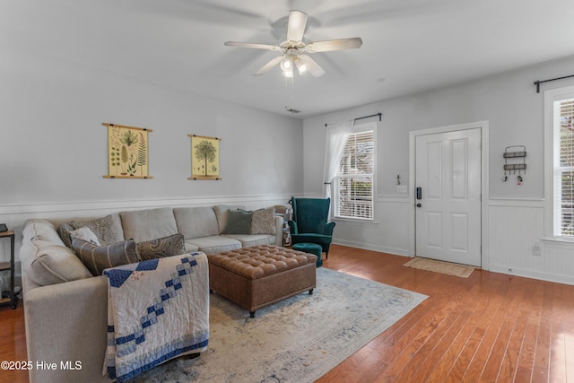 living room featuring a ceiling fan, a wainscoted wall, and hardwood / wood-style floors