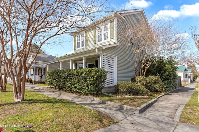 view of side of home with covered porch and a yard