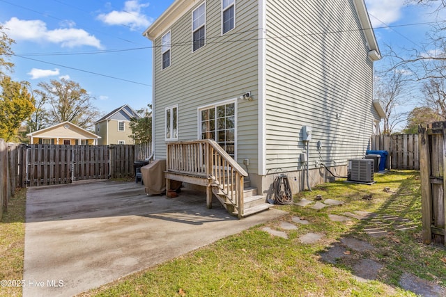 view of side of home with a fenced backyard, central AC, and a patio