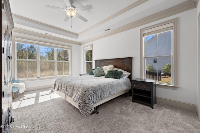 carpeted bedroom with a raised ceiling, multiple windows, visible vents, and ornamental molding