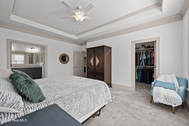 bedroom with a walk in closet, a raised ceiling, light colored carpet, and ornamental molding