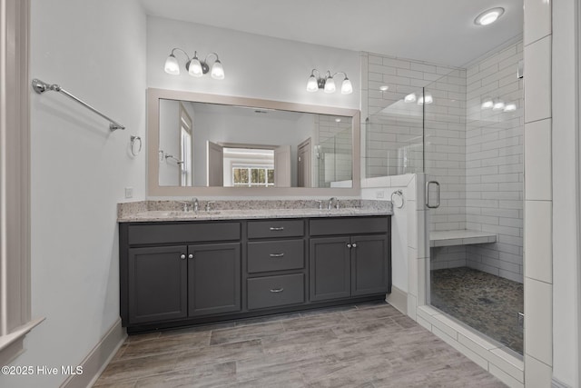 bathroom with a sink, wood finished floors, a stall shower, and double vanity