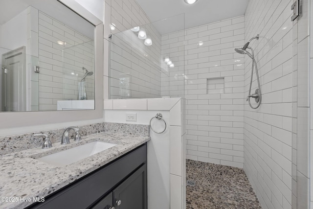 full bath featuring vanity and a tile shower